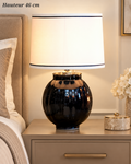 Lampe à poser de 46 cm avec pied arrondi noir brillant, détail doré et abat-jour crème bordé de liserés noirs.