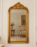 Miroir avec cadre en bois doré à la feuille, couronnement floral et volutes, 158 × 85 cm